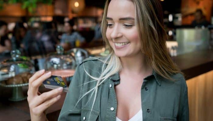 woman smiling and looking at card in hand